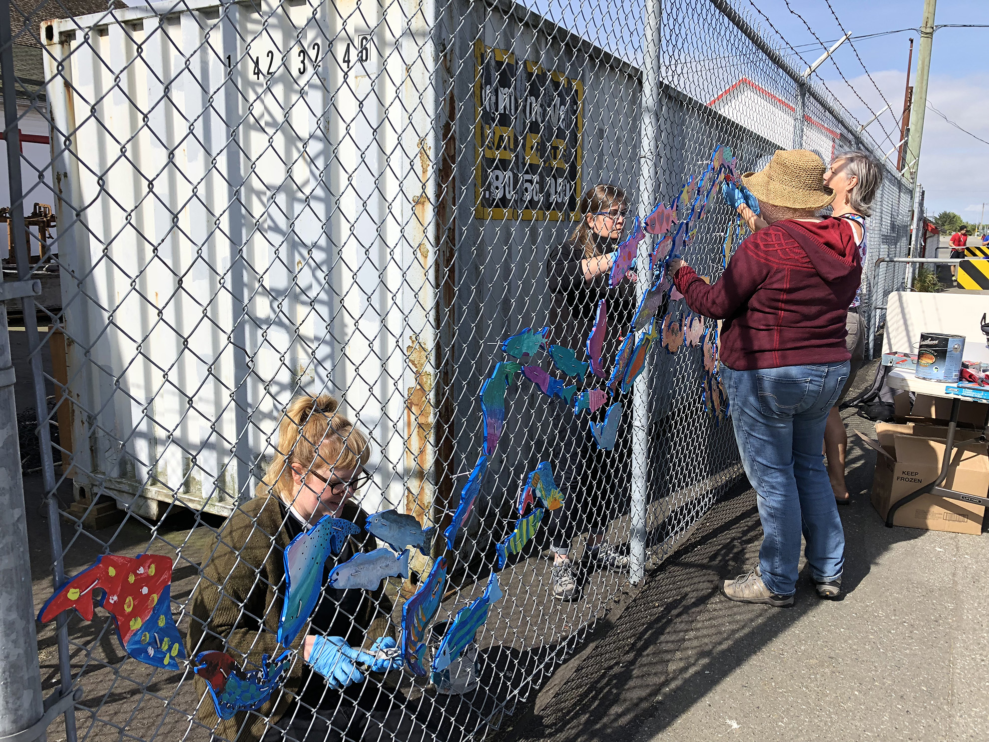 Stream of Dreams volunteers hanging up decorative fish art on fence