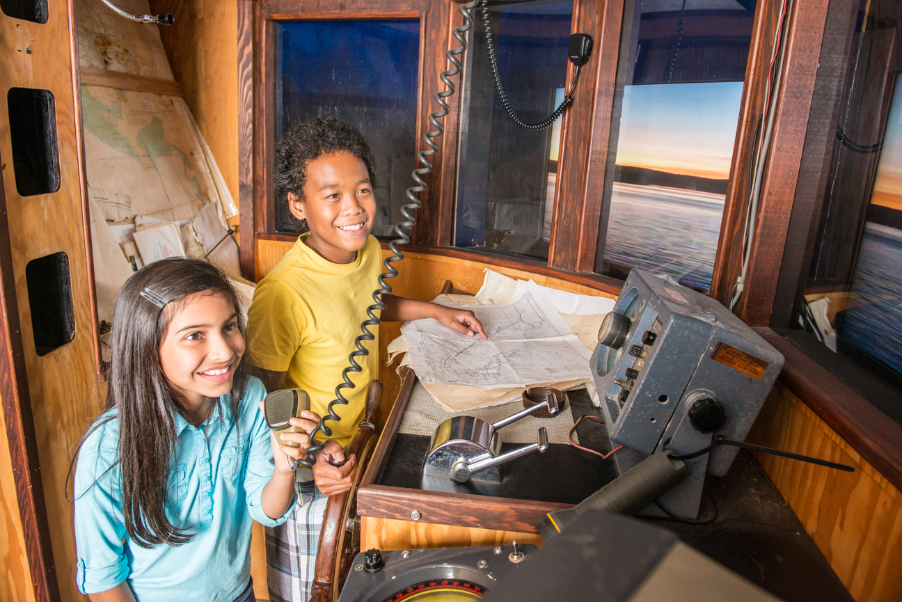 Two children in a a boat wheelhouse.