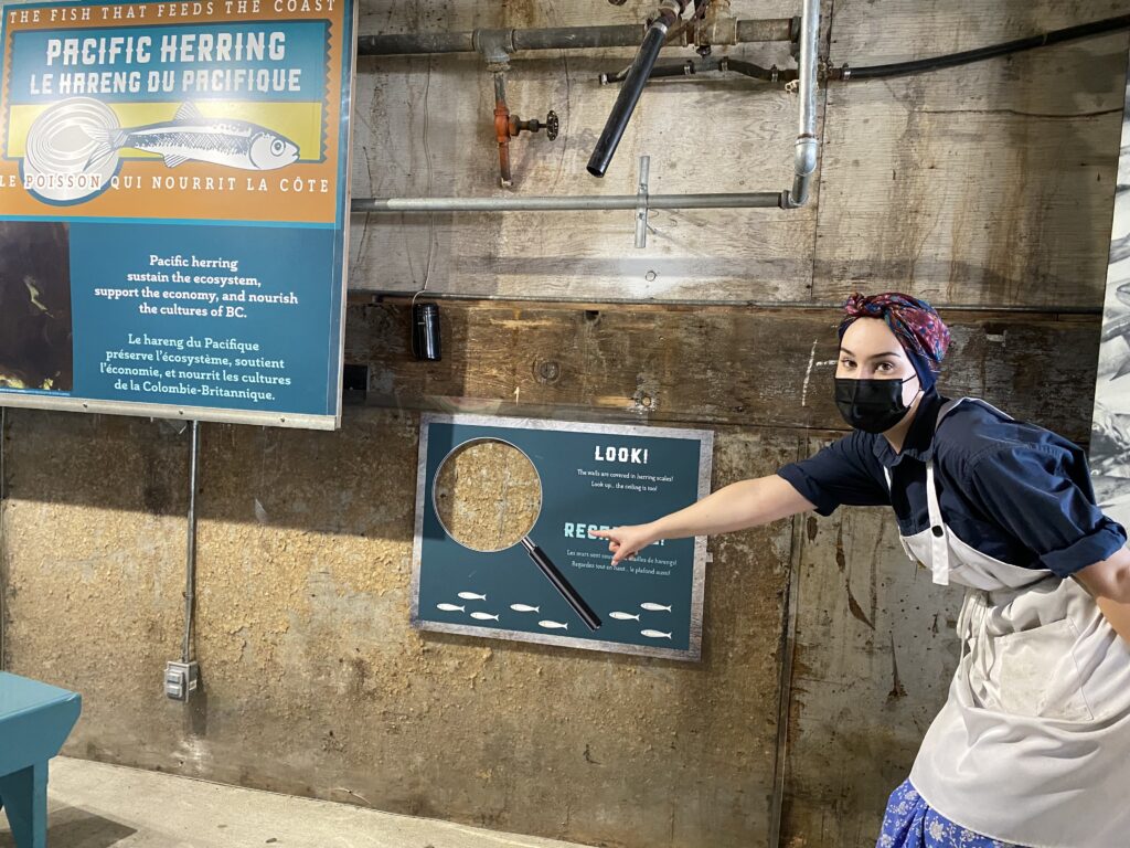 woman pointing to a sign depicting a large magnifying glass