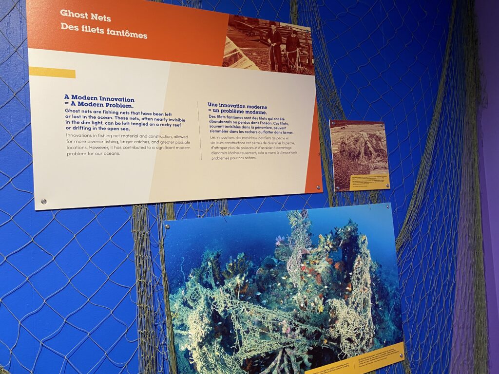 Orange panel with text and photo of ghost nets underwater on a blue wall