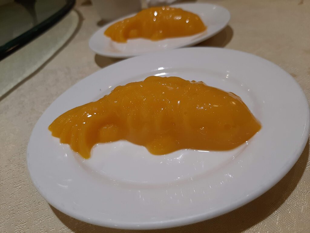 Fish-shaped orange jelly dessert on top of round white plate